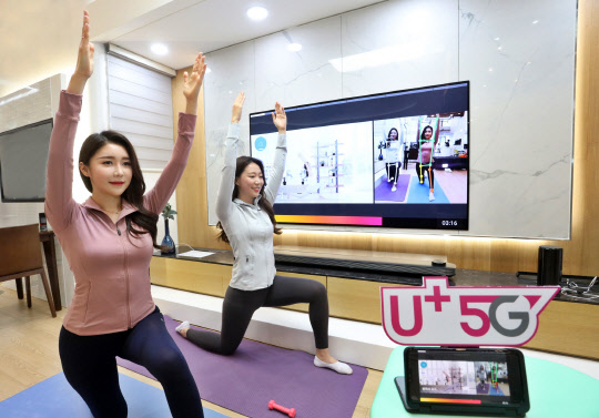 LG유플러스 모델이 실내에서  스마트폰을 이용해 5G 서비스 홈트를 이용하고 있다.    LG유플러스 제공